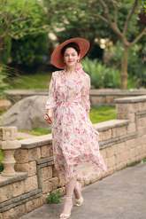 a lady in a pink floral printed dress with long sleeves